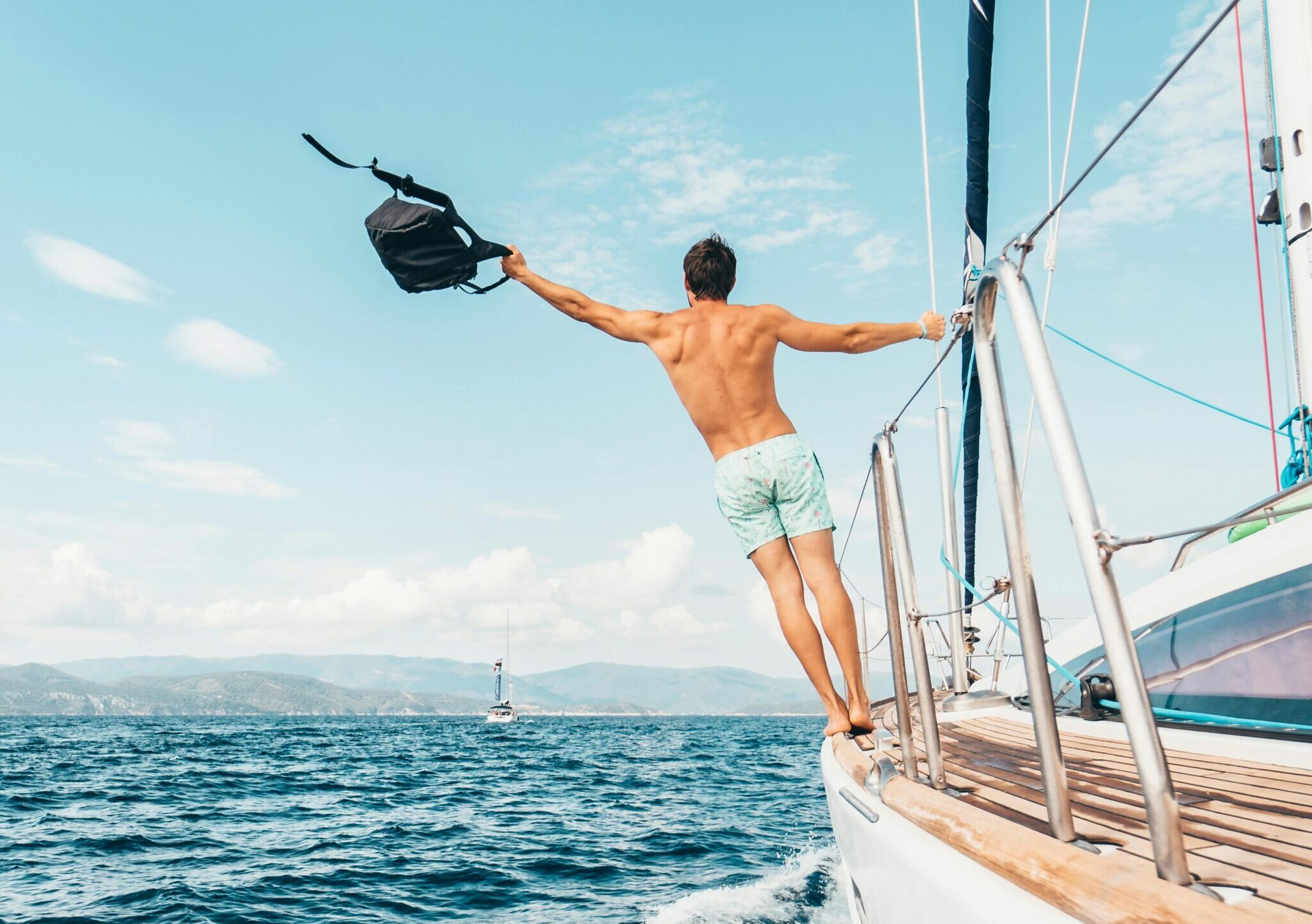 Man enjoying freedom by jumping into the ocean from a sailboat in Greece.